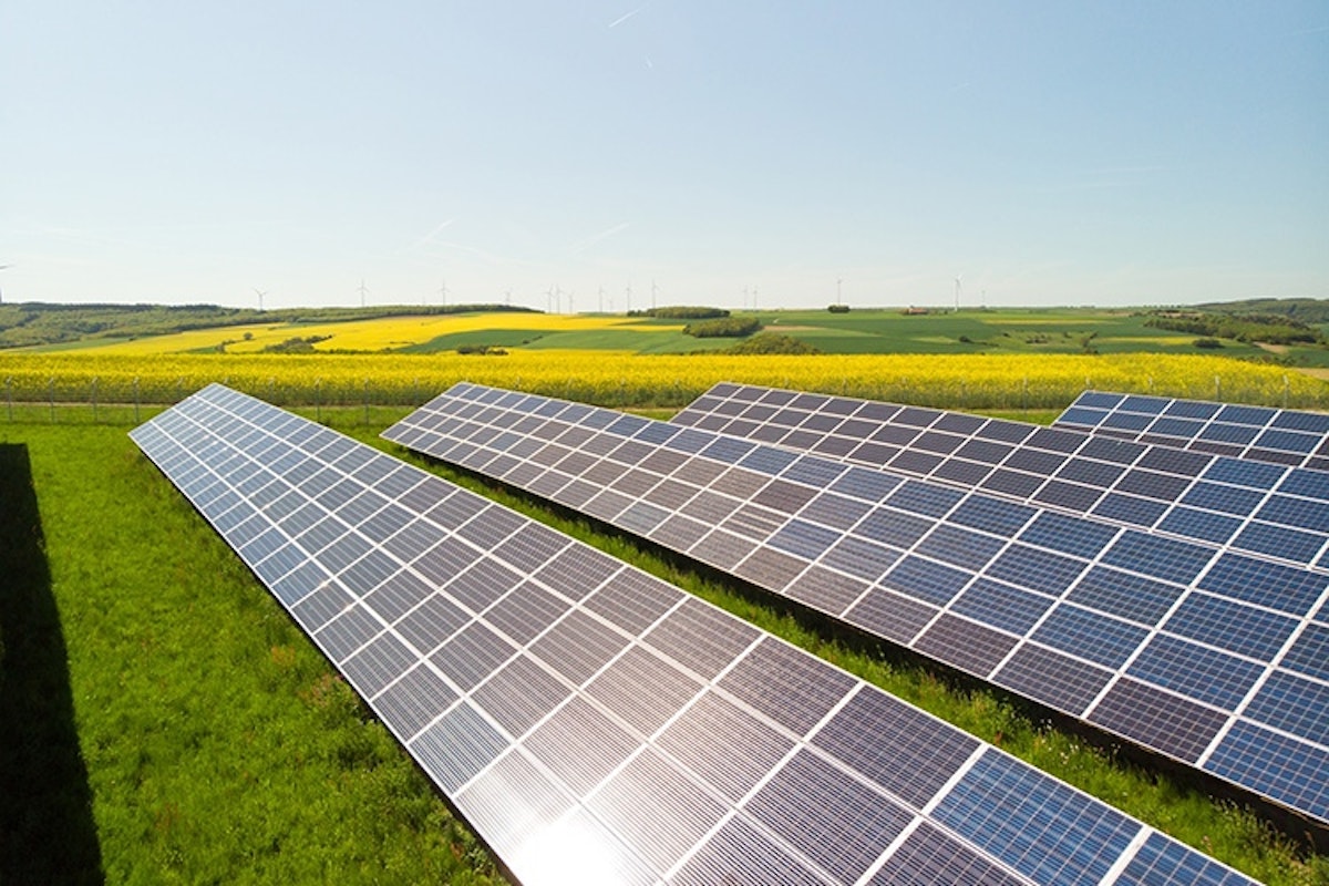 Solar panels on green grass against blue sky